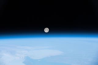 A pink moon hangs in the sky above the earth